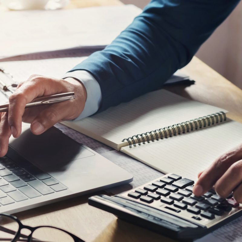 businessman workig and using calculator with laptop on desk